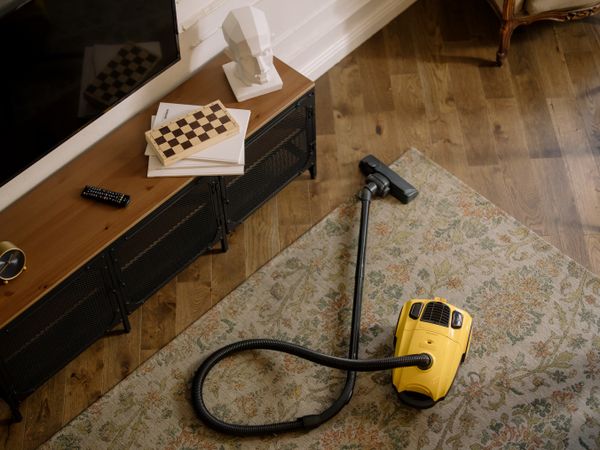 A cylinder vacuum cleaner on a rug